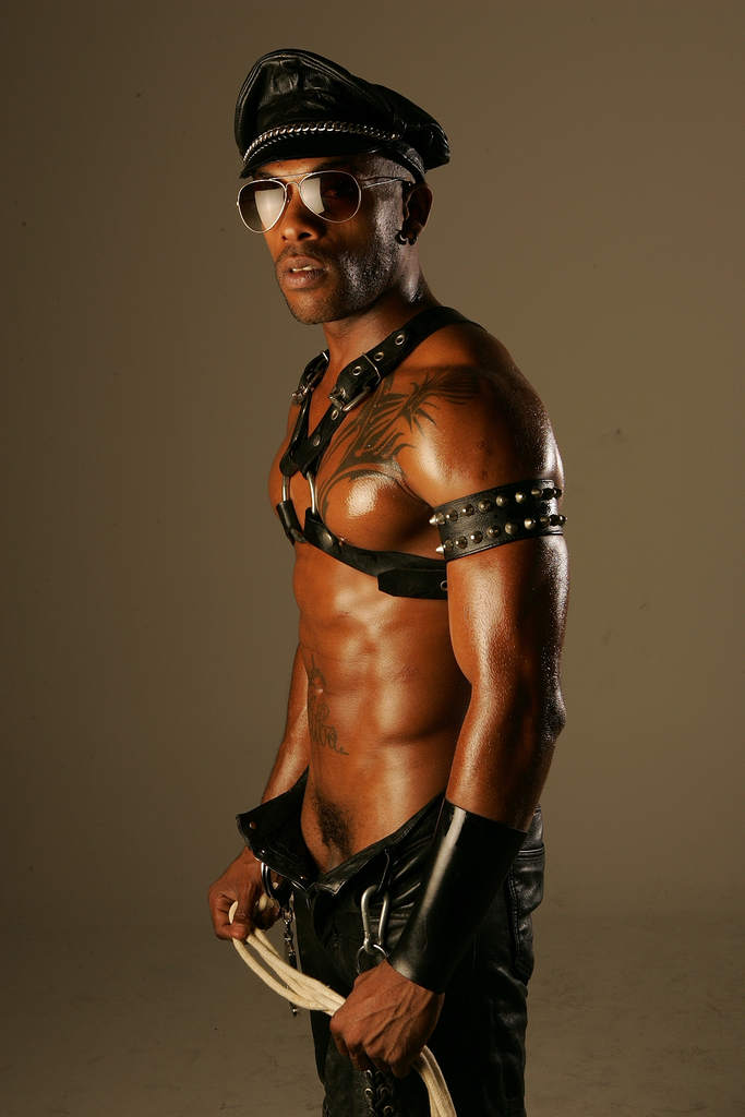 Kid Chocolate standing completely naked and showcasing his sculpted abs and chest under studio lights