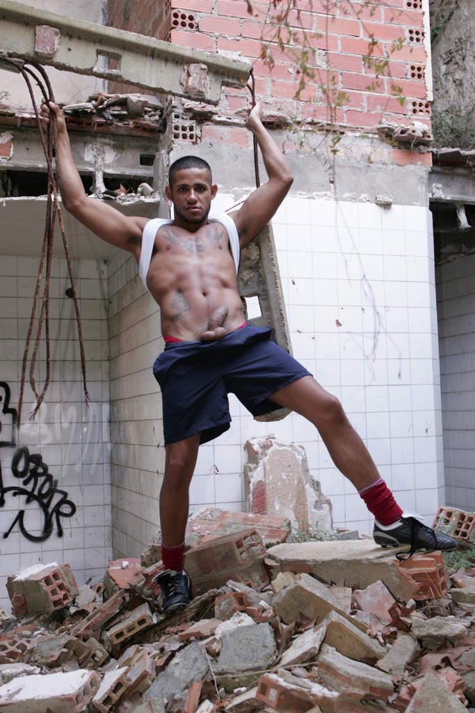 Fabio kneeling on industrial concrete, providing deep wet oral worship to Kid Chocolate's massive rod